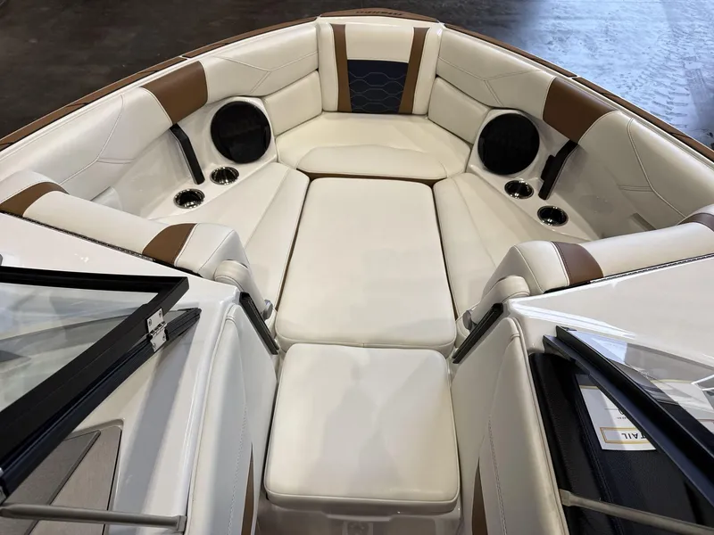 Slide: The Image of 2024 Malibu 23LSV boat interior with white and brown seating, cup holders, and speakers. - 8