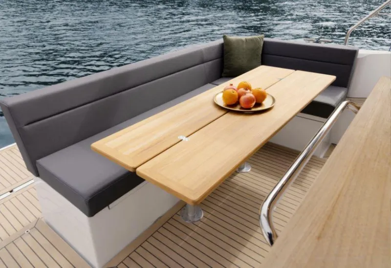 Slide: The Image of Sealine C335V 2025 boat interior with wooden table and cushioned seating by the water. - 20