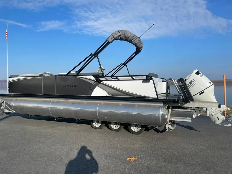 Slide: The Image of 2025 Avalon LSZ ELITE pontoon boat with Suzuki outboard motor on trailer. - 2