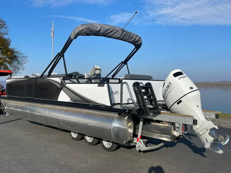 Slide: The Image of 2025 Avalon LSZ ELITE pontoon boat with Suzuki outboard motor, parked by a lake. - 3