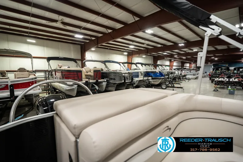 Slide: The Image of 2019 Bennington 21 SLX pontoon boat in showroom with multiple boats displayed. - 26