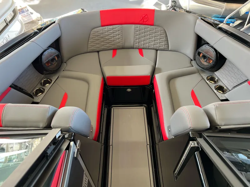Slide: The Image of 2025 MasterCraft X22 boat interior with gray and red seating, premium speakers, and cup holders. - 19