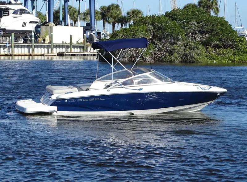 Slide: The Image of 2021 Regal 1900 ES Bowrider boat on water with blue canopy. - 1
