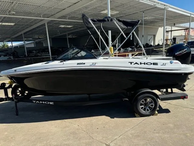 The Image of 2025 Tahoe 200 S boat with black hull and canopy, parked on a trailer. - 0