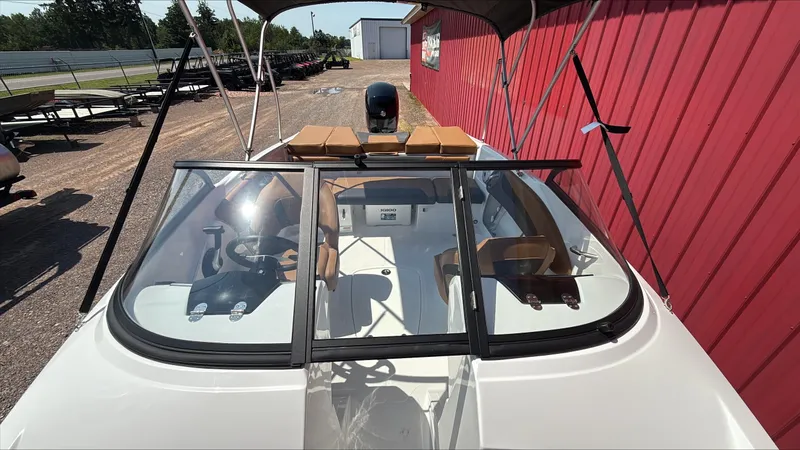 Slide: The Image of 2025 Tahoe 200 S boat with windshield and seating, parked near a red building. - 3