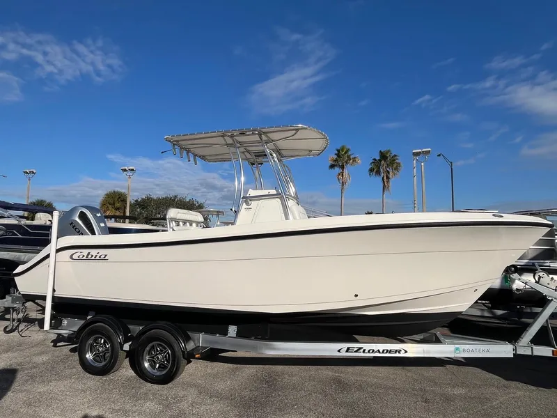 The Image of 2022 Cobia 237 Center Console boat on EZ Loader trailer under clear blue sky. - 0