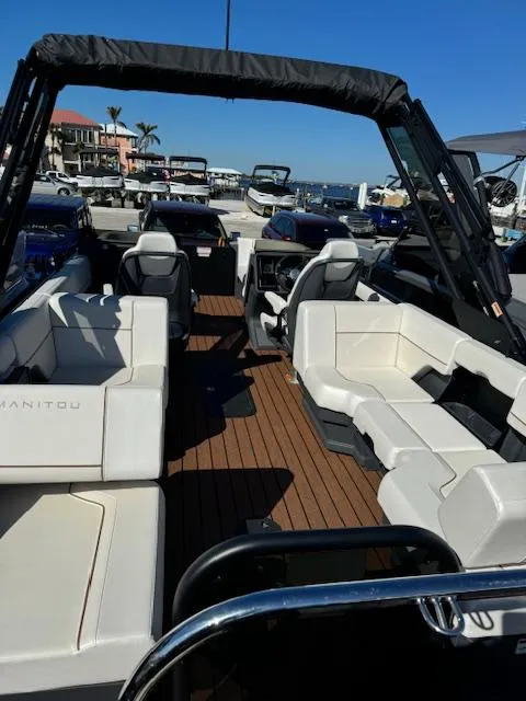 Slide: The Image of 2025 Manitou 22' Explore Navigator boat with spacious seating and sleek design at a marina. - 3