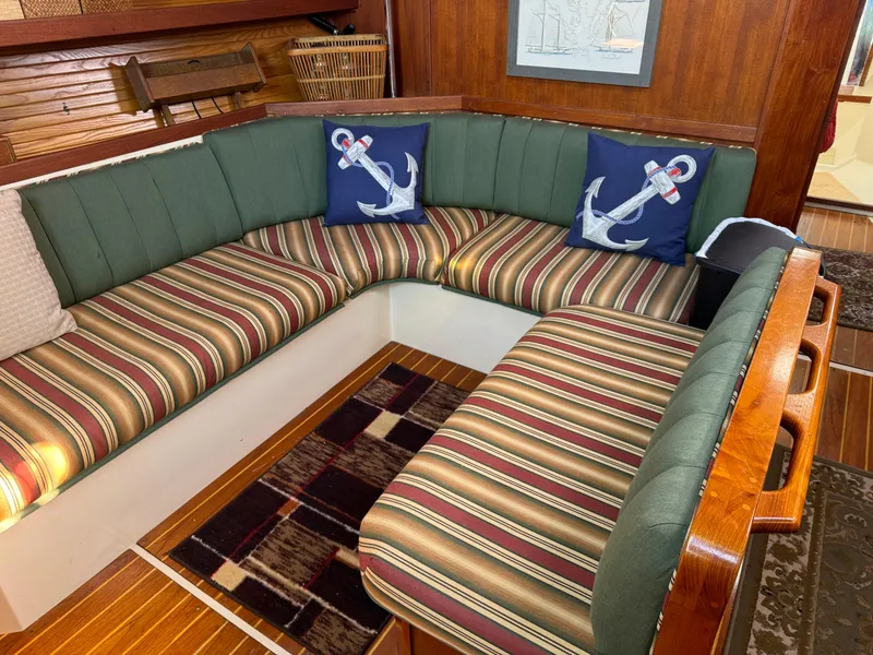 Slide: The Image of Cozy seating area in a 1989 Catalina 42 yacht with striped cushions and anchor-themed pillows. - 3