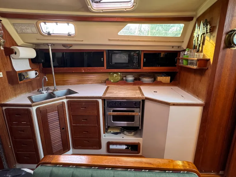 Slide: The Image of 1989 Catalina 42 yacht kitchen with wood cabinetry, sink, stove, and microwave. - 5