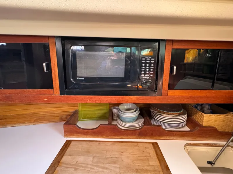 Slide: The Image of Galley of 1989 Catalina 42 sailboat with microwave and neatly arranged dishes. - 7