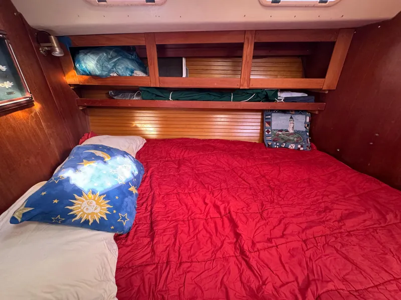Slide: The Image of Cozy cabin interior of 1989 Catalina 42 sailboat with red bedding and wooden shelves. - 9