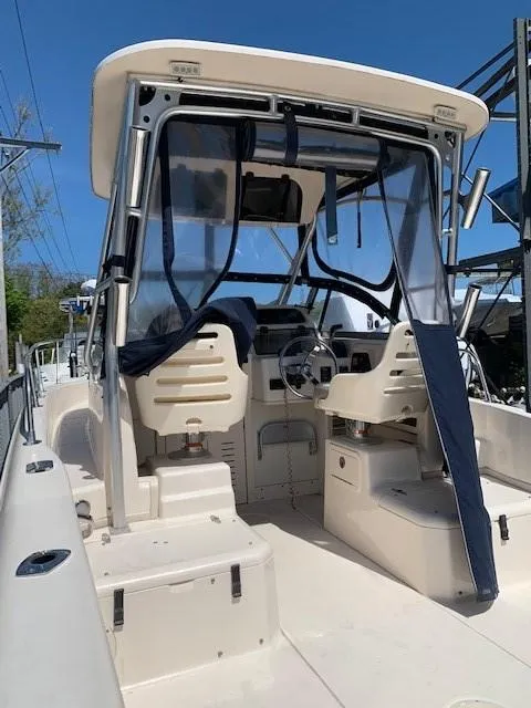 Slide: The Image of 2014 Grady-White Seafarer 226 boat interior with helm and seating, under clear blue sky. - 4