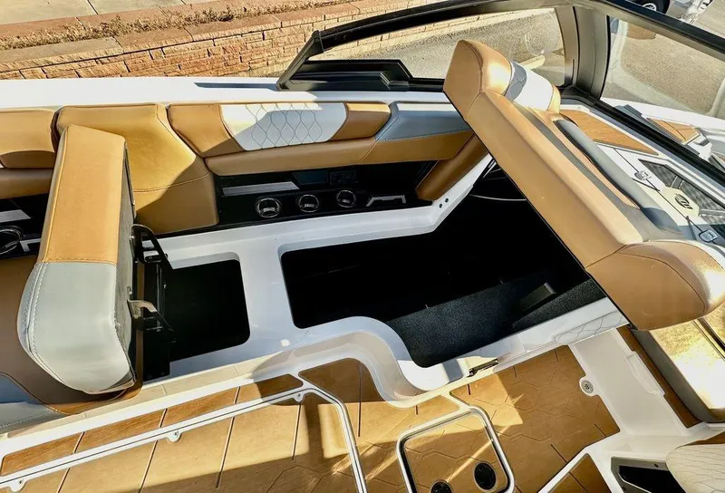 Slide: The Image of 2023 Malibu M220 boat interior with tan and gray seating, open storage compartments. - 11