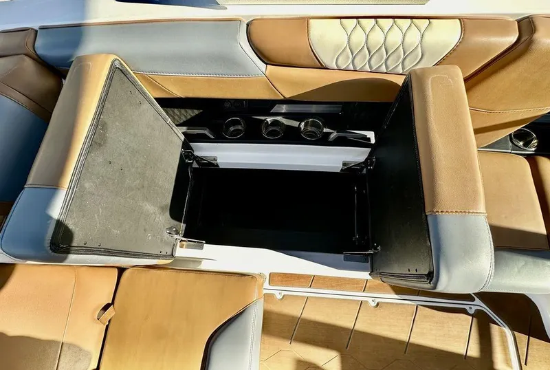Slide: The Image of 2023 Malibu M220 boat interior with open storage compartment and tan leather seats. - 12