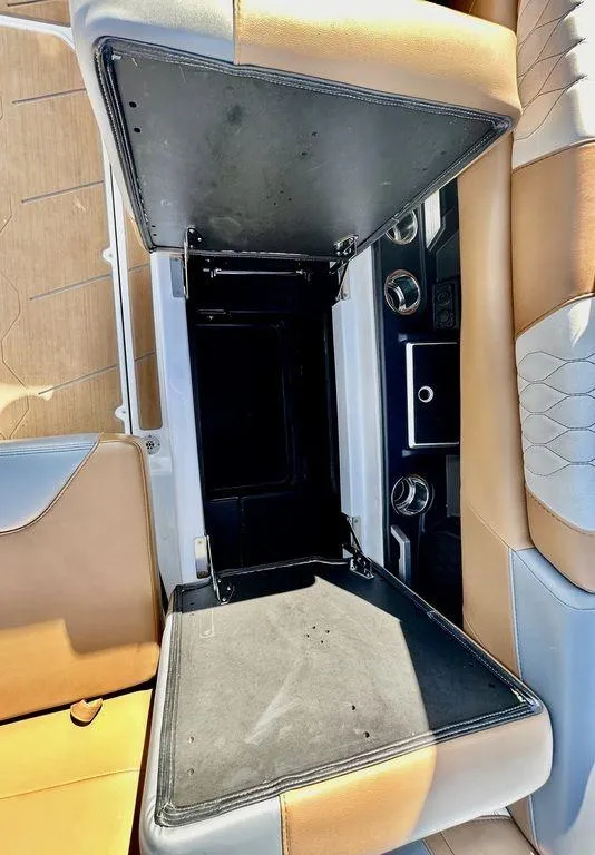 Slide: The Image of 2023 Malibu M220 boat interior storage compartment with tan and gray seating. - 13