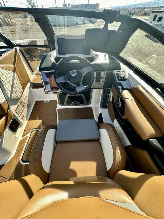 Slide: The Image of 2023 Malibu M220 boat interior with modern dashboard and tan leather seating. - 14