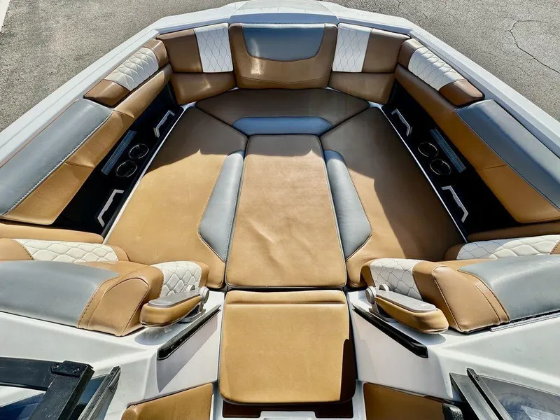 Slide: The Image of 2023 Malibu M220 boat interior with tan and gray seating, cup holders, and spacious layout. - 15