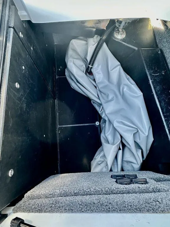 Slide: The Image of 2023 Malibu M220 storage compartment with gray cover and black interior. - 17