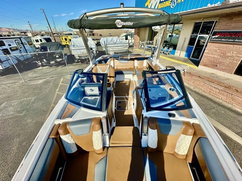 Slide: The Image of 2023 Malibu M220 boat with luxurious seating and sleek design at a dealership. - 19