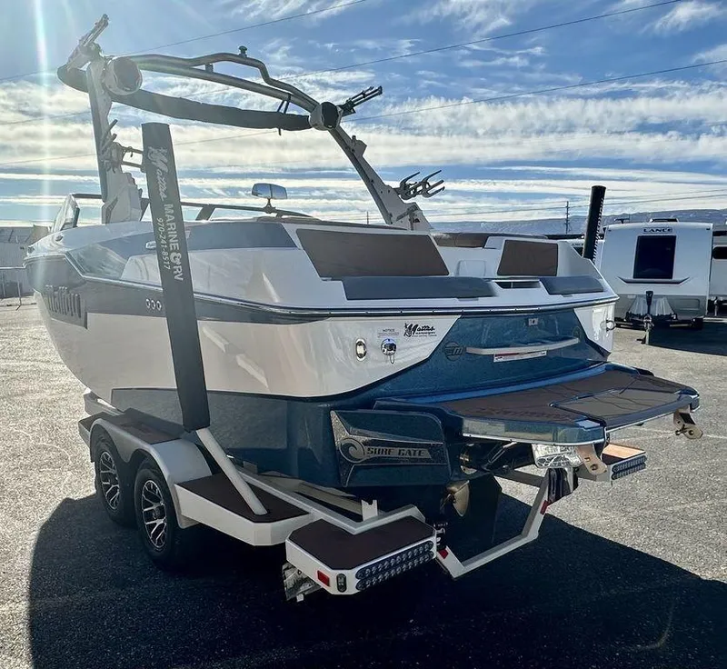 Slide: The Image of 2023 Malibu M220 boat on trailer under a cloudy sky. - 5