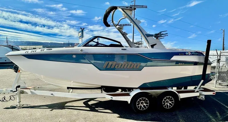 Slide: The Image of 2023 Malibu M220 boat on trailer under blue sky. - 6