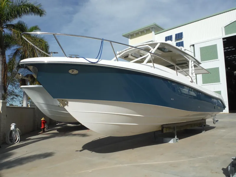 Slide: The Image of 2017 Everglades 360LXC boat in marina, blue and white hull, docked near palm trees. - 15