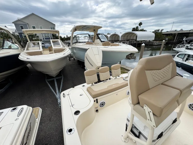 Slide: The Image of 2024 Scout 231 XSB boat with beige seating, docked alongside other boats. - 10
