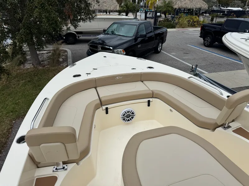 Slide: The Image of 2024 Scout 231 XSB boat with beige seating and speaker, parked in a lot. - 8