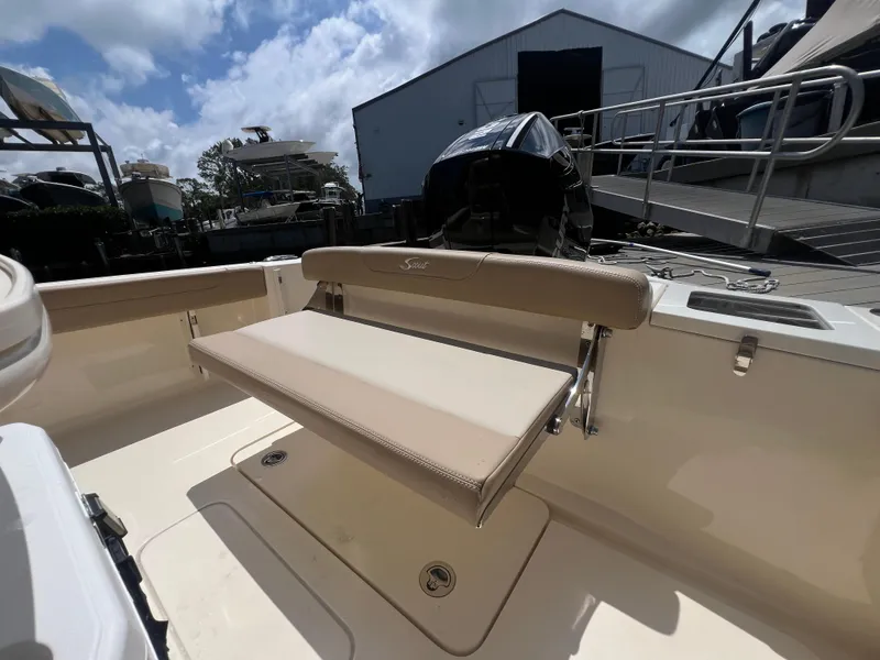 Slide: The Image of 2025 Scout 215 XSF boat interior with foldable seat and motor, under a partly cloudy sky. - 10