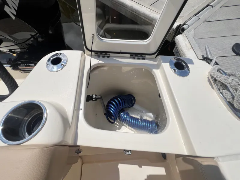 Slide: The Image of 2025 Scout 215 XSF boat storage compartment with coiled blue hose. - 11
