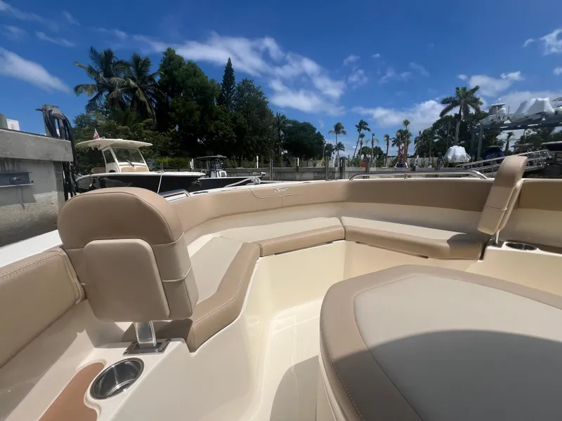 Slide: The Image of 2025 Scout 215 XSF boat interior with beige seating, docked under a clear blue sky. - 2