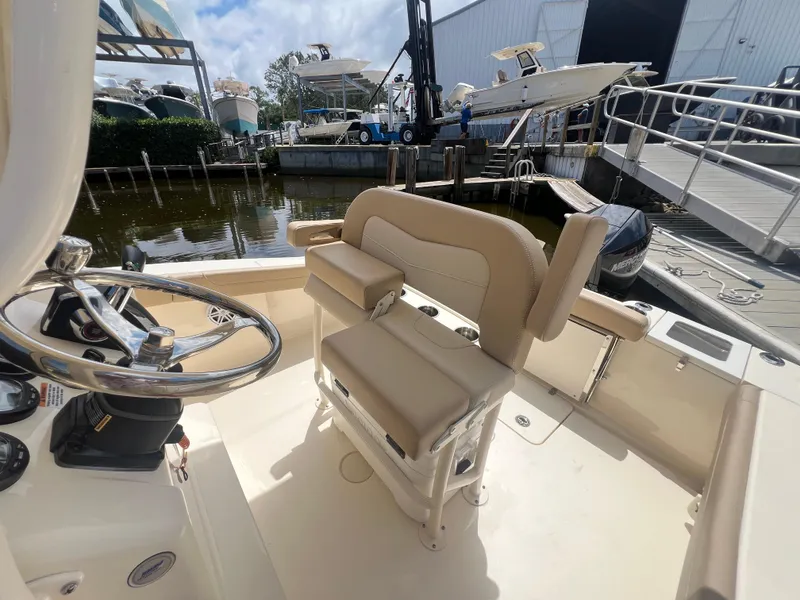 Slide: The Image of 2025 Scout 215 XSF boat interior with steering wheel and seating at marina. - 8