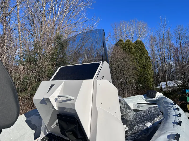 Slide: The Image of 2023 Highfield Sport 700 boat with console, surrounded by trees under clear blue sky. - 5