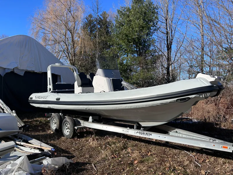 Slide: The Image of 2023 Highfield Sport 700 boat on trailer, parked outdoors in a wooded area. - 6