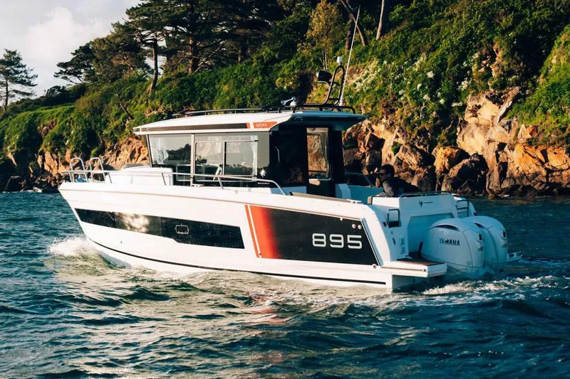 Slide: The Image of 2025 Jeanneau NC 895 Sport Series 2 boats with dual outboard engines at a marina. - 2