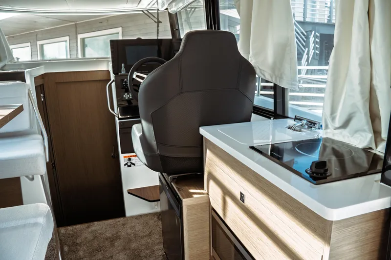 Slide: The Image of Interior of 2025 Jeanneau NC 895 Sport Series 2, featuring helm and compact kitchen area. - 21