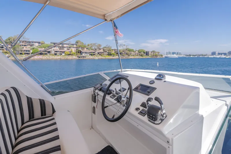 Slide: The Image of 2007 Navigator Pilothouse yacht helm with striped seating, overlooking serene waterfront. - 34