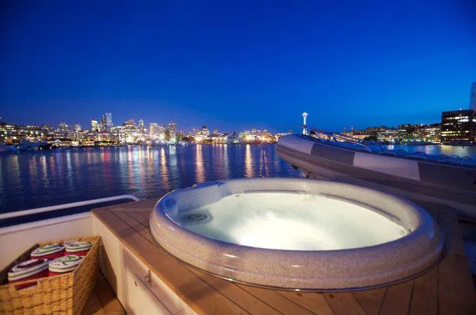 Slide: The Image of Luxurious Broward 105 yacht with hot tub, city skyline view, evening ambiance, 1991 model. - 14