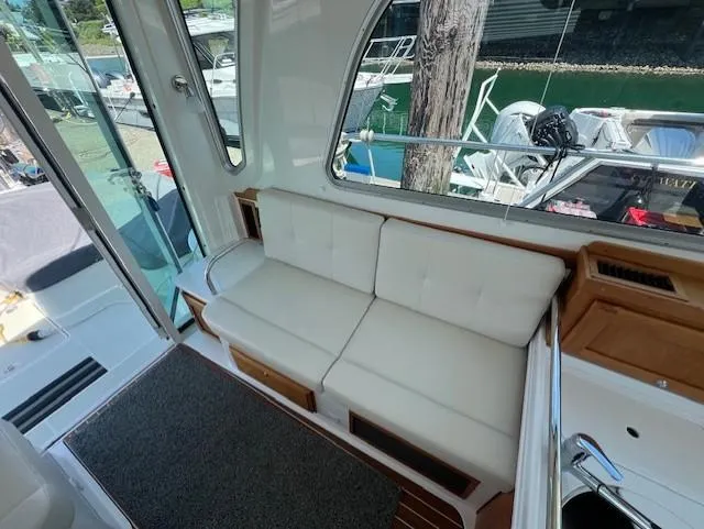 Slide: The Image of 2020 Back Cove 37 interior with white seating and wooden accents, docked by the water. - 9