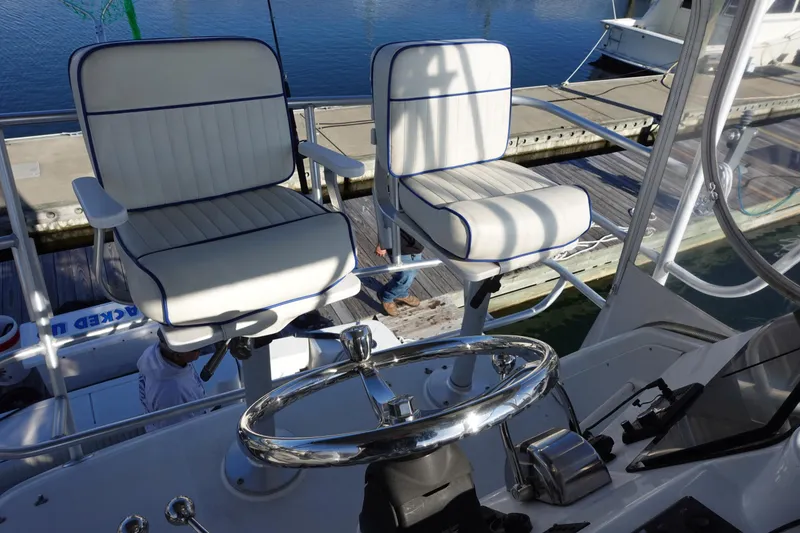 Slide: The Image of 2001 Luhrs 36 Convertible boat helm with dual white cushioned seats and steering wheel. - 15
