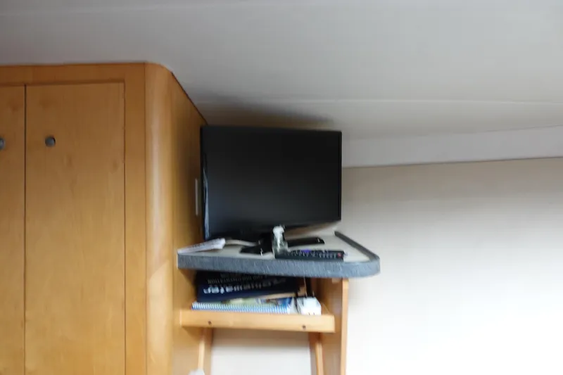 Slide: The Image of 2001 Luhrs 36 Convertible interior with mounted TV and wooden cabinet. - 28