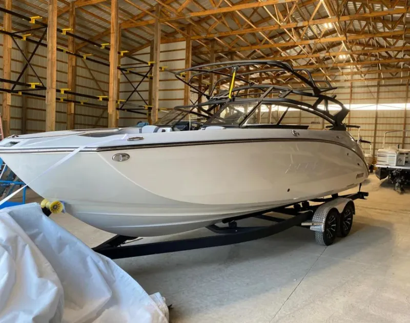 Slide: The Image of 2024 Yamaha Boats 255XE in storage, sleek design, white exterior, on trailer. - 3