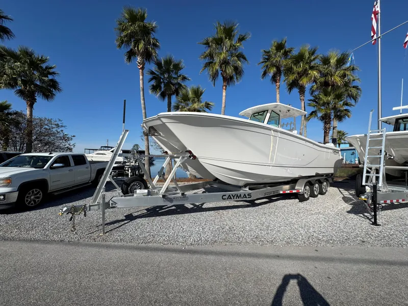 Slide: The Image of 2025 Caymas 34 CT boat on trailer, parked near palm trees under clear blue sky. - 0