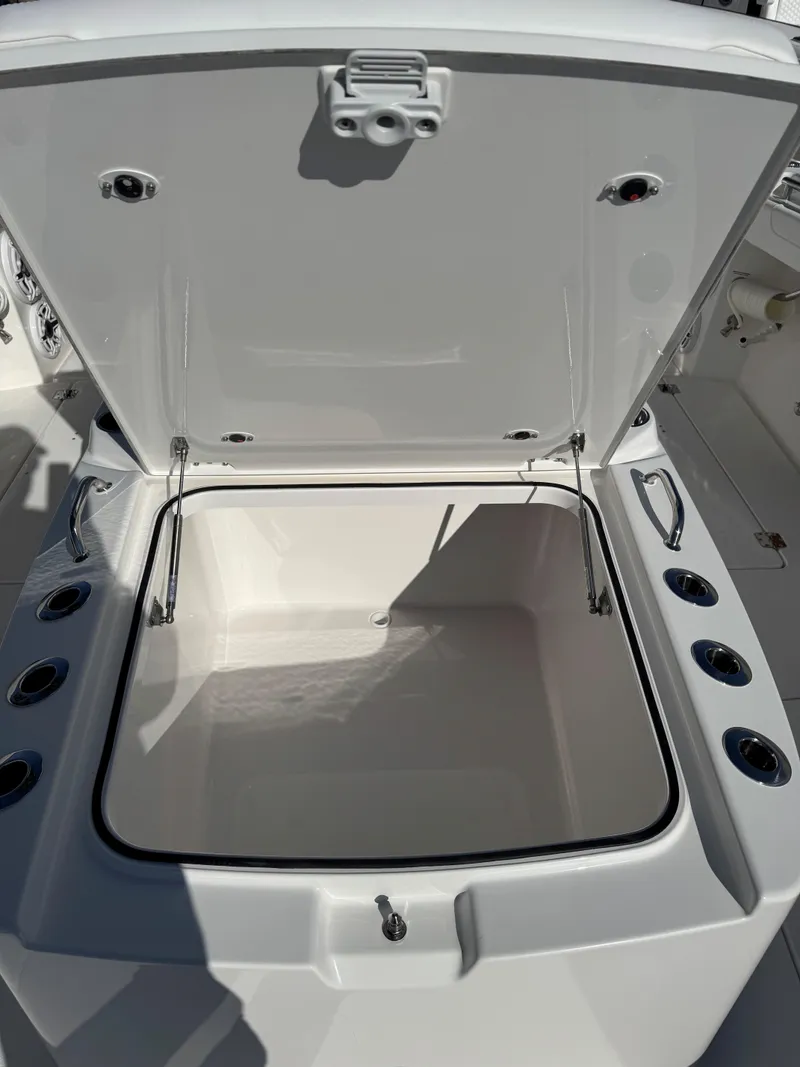 Slide: The Image of 2025 Caymas 34 CT boat storage compartment with open lid and cup holders. - 12