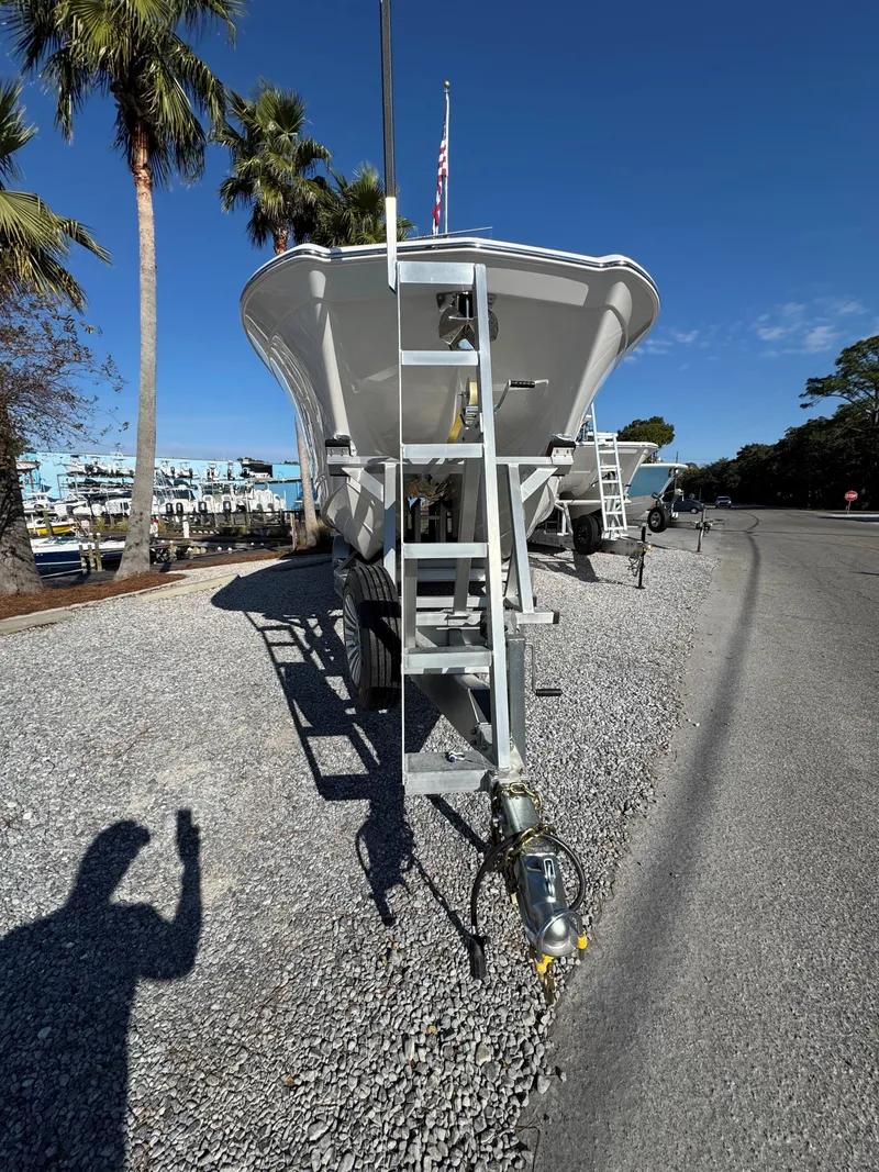Slide: The Image of 2025 Caymas 34 CT boat on trailer, parked on gravel, with palm trees in background. - 9