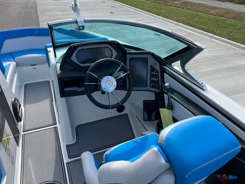 Slide: The Image of 2018 MasterCraft XStar boat interior with blue and white seating and modern dashboard. - 9