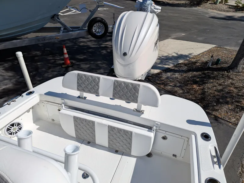 Slide: The Image of 2025 BlackJack 256 Coastal boat interior with seating and motor, parked on trailer. - 26