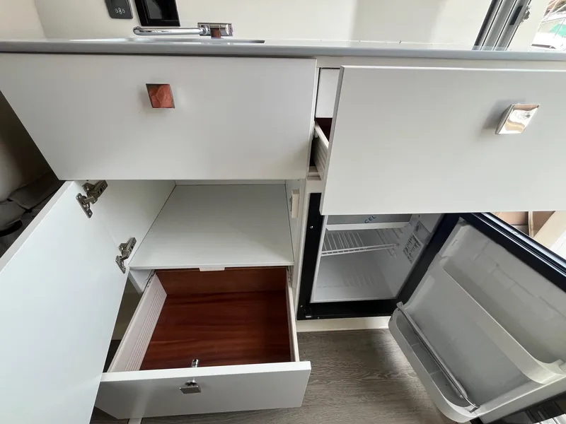 Slide: The Image of Interior view of 2025 Bayliner Trophy T25 Explorer kitchen with open cabinets and fridge. - 11