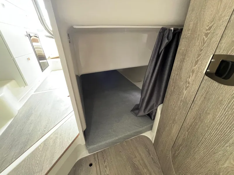 Slide: The Image of 2025 Bayliner Trophy T25 Explorer cabin interior with wood finish and storage space. - 17