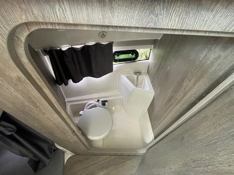 Slide: The Image of Compact bathroom in 2025 Bayliner Trophy T25 Explorer boat, featuring toilet and sink. - 18